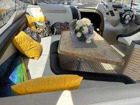 Cozy interior of a boat featuring comfortable seating with decorative pillows and a dining table, perfect for relaxing and enjoying the marine environment.