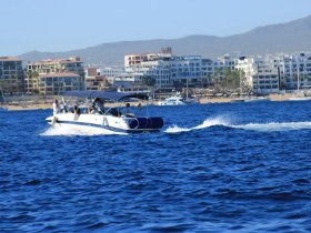 A lively group enjoys a day on the water aboard a speedboat, cruising along the beautiful coastline with scenic views of the shore.