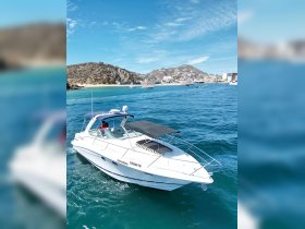 A sleek speedboat named 'Coqueto' navigates through clear waters, showcasing the stunning coastal scenery of Cabo San Lucas.