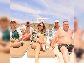 A cheerful group enjoys a sunny day on a boat, relaxing and sunbathing — perfect for a fun day out on the water.