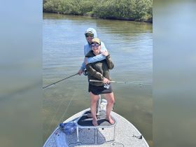 A joyful couple enjoys a fishing trip on a boat, showcasing the fun and adventure of outdoor water activities.