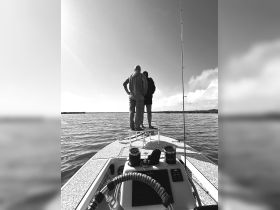 Two individuals enjoy a scenic view from the bow of a boat, perfect for fishing adventures and water exploration.