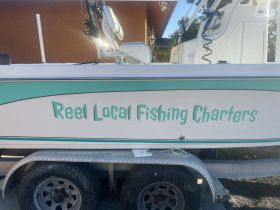A close-up view of a fishing charter boat named 'Reel Local Fishing Charters' — perfect for those looking to enjoy a day on the water fishing.