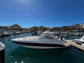 A sleek yacht docked at a marina, showcasing the vibrant surroundings and clear blue skies — perfect for luxury boating experiences.
