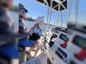 A joyful moment as a child steers the boat with guidance from an adult, capturing the essence of family fun on the water.
