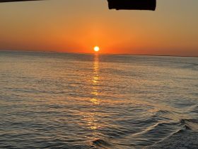 A stunning sunset over calm waters, captured from a boat, creating a picturesque backdrop for evening cruises.