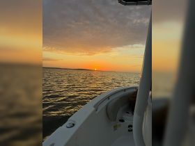 A serene sunset view from the deck of a boat, showcasing the tranquil waters and vibrant sky — perfect for evening cruises.