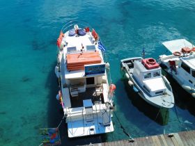 Aerial view of a yacht docked in crystal-clear waters, showcasing its vibrant colors and inviting deck — perfect for leisure and exploration.
