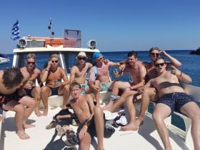 A lively group of friends enjoys drinks and fun on a boat, capturing the essence of a perfect summer day at sea.