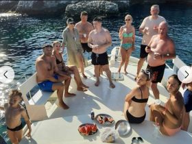 A lively group enjoys a sunny day on a boat, celebrating with drinks and snacks — perfect for a fun-filled outing on the water.