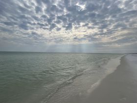 A serene view of a beach with cloudy skies and gentle waves, creating a tranquil atmosphere perfect for relaxation.