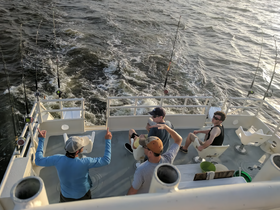 A group of friends enjoys a fishing trip on a boat, with rods ready and laughter in the air — perfect for a day of adventure on the water.