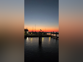 A serene sunset view over the harbor, with a silhouette of a bird perched on a post, creating a picturesque scene perfect for evening reflections.