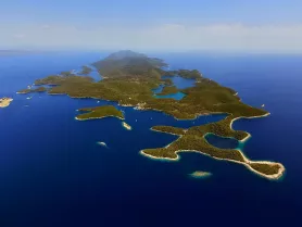 A stunning aerial view of a picturesque island landscape, showcasing the vibrant blue waters and lush greenery — perfect for exploring by boat or enjoying a scenic cruise.