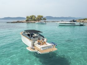 A couple enjoys a relaxing moment aboard the 'Duchess' boat in crystal-clear turquoise waters, surrounded by scenic islands — perfect for a romantic getaway or day trip.