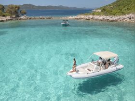 A group enjoys a sunny day on a boat in crystal-clear waters, perfect for island hopping and aquatic adventures.