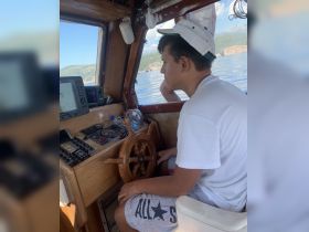 A young person navigates from the helm of a boat, showcasing the interior cabin and control console — perfect for those learning to steer or enjoying a day on the water.