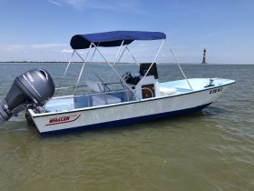 A Boston Whaler boat docked in calm waters, showcasing its sleek design and structure against a clear blue sky.