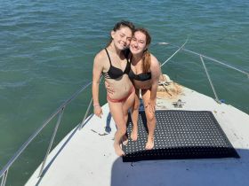 Two friends enjoy a sunny day on the boat, showcasing a fun moment of celebration and camaraderie while enjoying the water.