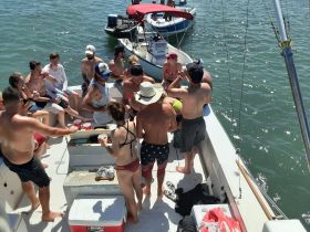 A lively group enjoys drinks and camaraderie aboard a boat, perfect for summer parties and celebrations on the water.