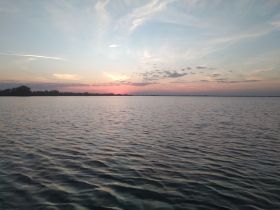 A serene sunset over calm waters, showcasing the beauty of nature — perfect for tranquil evening boat rides.