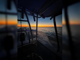 A serene view from the helm of a boat during sunset, showcasing the tranquil waters and the fading light on the horizon — perfect for evening cruises.