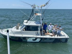 A group of friends celebrates their successful fishing trip aboard a boat, proudly displaying their catch in the sunlit waters.