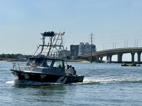 A fishing boat navigates through the waterway, showcasing a lively day on the water with friends. Perfect for fishing trips or leisurely outings.