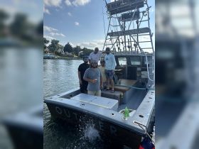 A group of friends enjoys a day out on the water aboard the 'Outlier,' celebrating with drinks and camaraderie. Perfect for fishing trips or summer outings.