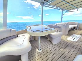 A spacious interior view of a boat's lounge area featuring comfortable seating and a table, perfect for relaxing while enjoying the ocean views.