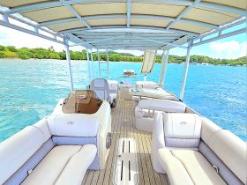 A spacious interior view of a boat's lounge area, featuring comfortable seating and a serene backdrop of turquoise waters, perfect for relaxing on a day out at sea.