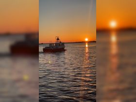 A serene sunset view of a boat cruising on calm waters, creating a picturesque scene perfect for evening outings.