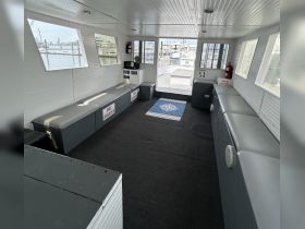 Interior view of a spacious boat cabin featuring comfortable seating and safety equipment, ideal for relaxing during a day on the water.