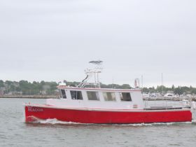A striking red boat named 'Beacon' glides through the water, showcasing its sleek design and perfect for various maritime adventures.