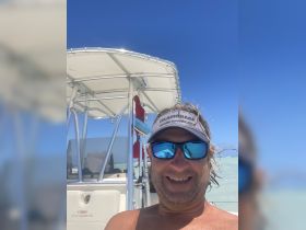 A cheerful selfie taken on a Cobia boat under a clear blue sky, perfect for capturing memorable moments on the water.