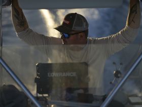 A focused individual navigates the helm of a boat, showcasing the interior console and the thrill of boating adventures.