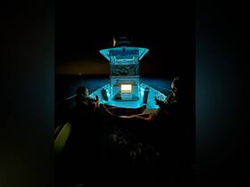 A couple enjoys a serene night on the water aboard the 'Dream Catcher,' illuminated by soft blue lights — perfect for a relaxing evening getaway.