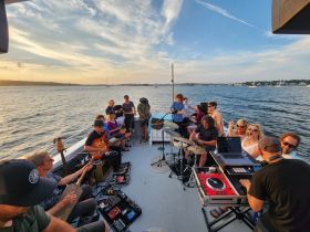 A lively group enjoys a sunset music session aboard a boat, creating a vibrant atmosphere perfect for celebrations and gatherings on the water.
