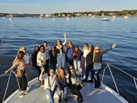 A lively group of friends celebrates aboard a boat, enjoying the beautiful waterfront scenery — perfect for memorable outings and sunset cruises.