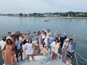 A lively group of friends celebrates aboard a boat, waving and enjoying their time on the water — perfect for memorable gatherings and parties.