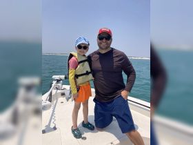 A joyful moment captured on a boat, featuring a father and son smiling together in life jackets, perfect for family outings on the water.