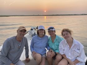 A cheerful group enjoys a sunset on the water, capturing a memorable moment aboard their boat — perfect for family outings and celebrations.