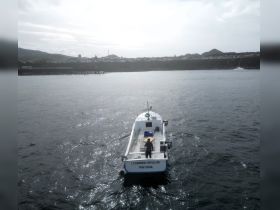 A fishing boat named 'Leonardo da Gilda' navigates the waters off the coast of Portugal, showcasing its sleek design against a scenic backdrop.