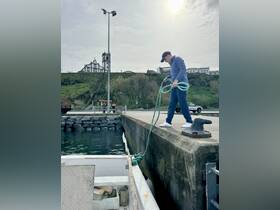 A man prepares to secure a boat at the dock, showcasing the vibrant harbor atmosphere — perfect for fishing trips or boating adventures.