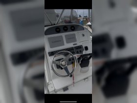 A detailed view of the helm and console of a boat, showcasing the Garmin navigation equipment and steering wheel, ideal for navigating the waters.
