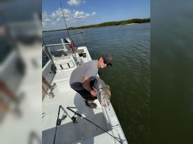 A young angler proudly displays his catch aboard a fishing boat, showcasing the thrill of a successful day on the water.