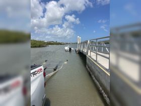 A small boat is docked at a marina with a clear blue sky overhead, showcasing a serene boating environment perfect for fishing or leisure activities.