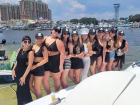 A lively group of friends celebrates a bachelorette party on a boat, showcasing fun and camaraderie against a vibrant waterfront backdrop.