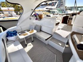A stylish interior view of a boat's cabin featuring comfortable seating and a table, perfect for relaxing or dining while on the water.