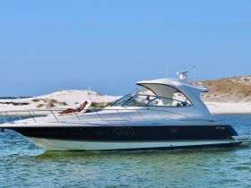 A person relaxes on the deck of a stylish boat, enjoying the sun and beach views — a perfect scene for leisure and relaxation on the water.